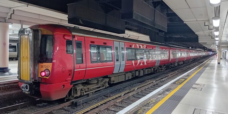 A red Gatwick Express train with a yellow front at a platform in London Victoria station
