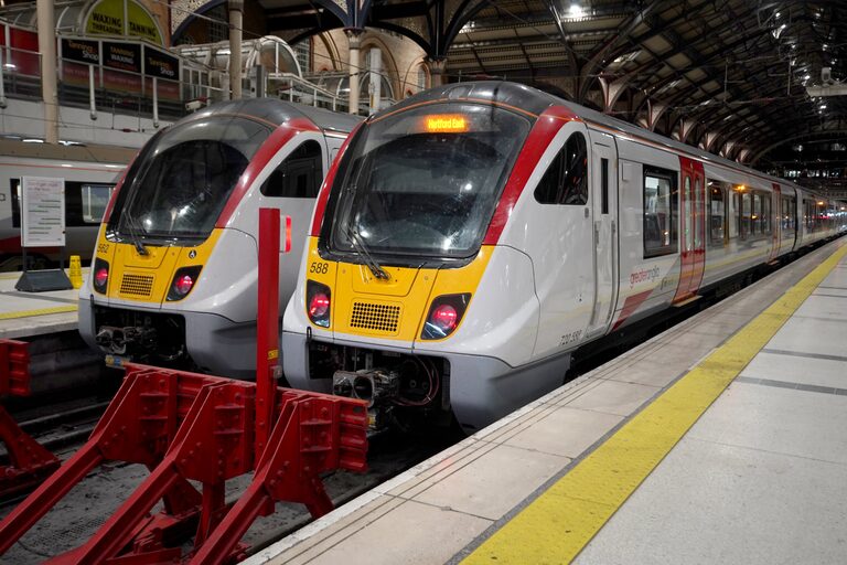 Two white Greater Anglia trains with yellow fronts side by side at red buffer stops in London Liverpool Street station