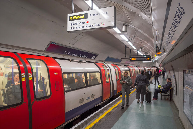 A Tube train with red doors at a curved underground platform, under a Way out sign to Regent's Canal, King's Cross and St Pancras International
