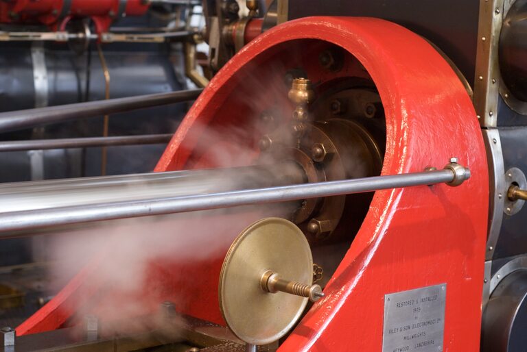 Close-up of a big red steam engine in motion, its steel rods blurred