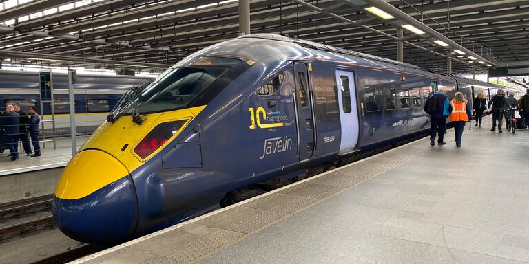 A dark blue Southeastern high-speed train with a long yellow nose and the word Javelin on its side, at a platform in St Pancras International station