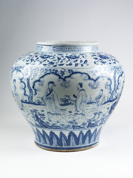 A large, round blue and white porcelain jar painted with figures in a garden