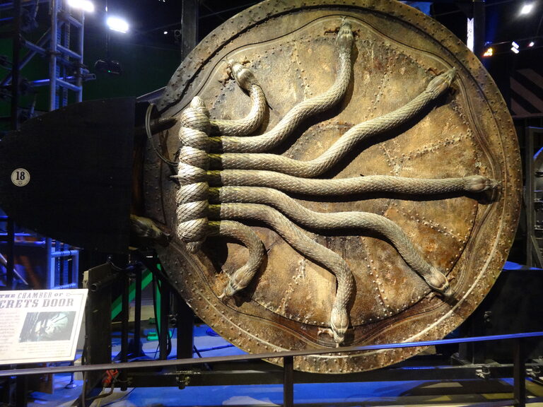 The big round Chamber of Secrets door, with carved snakes coiled across it, on a stand under studio lights